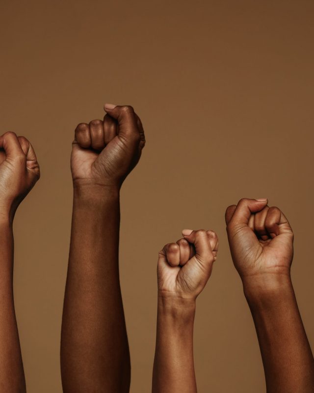 Cropped,Shot,Of,Hands,Raised,With,Closed,Fists.,Multiple,Hands